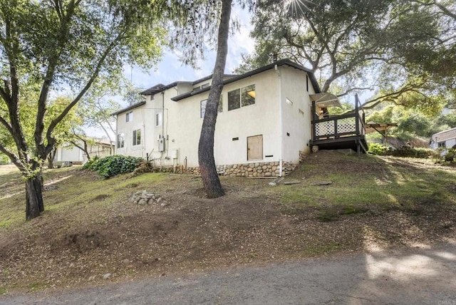 view of side of home with a wooden deck and stucco siding