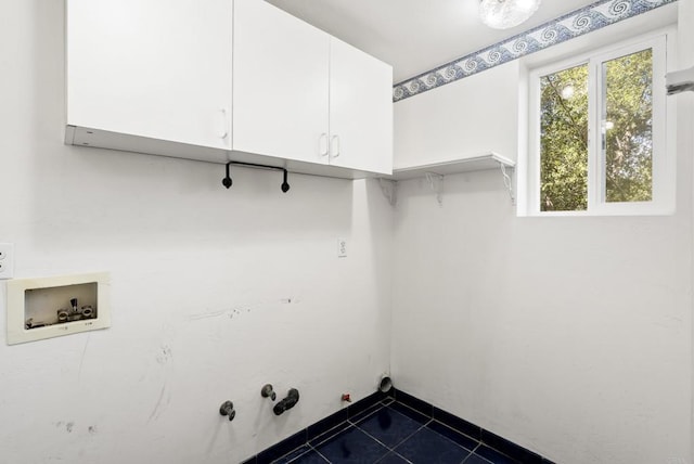 washroom featuring cabinet space, washer hookup, hookup for a gas dryer, and dark tile patterned flooring