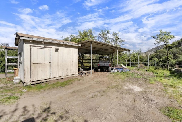 view of parking / parking lot with a carport, dirt driveway, and a storage shed