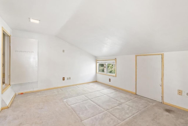 bonus room featuring baseboards, lofted ceiling, and light carpet
