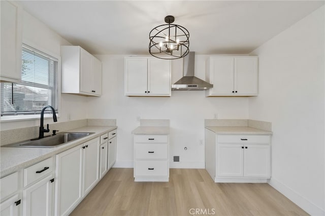 1559 N Carruth Ave, Fresno, CA 93728 - kitchen with wall chimney range hood, a sink, white cabinets, a chandelier, and light wood-style floors