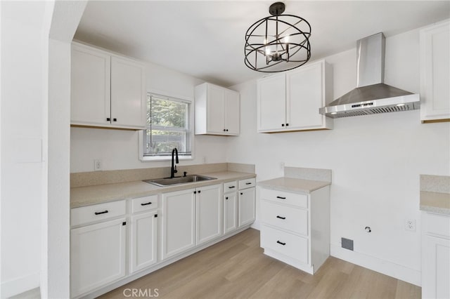 1559 N Carruth Ave, Fresno, CA 93728 - kitchen featuring white cabinets, a sink, light wood-style flooring, wall chimney exhaust hood, and pendant lighting