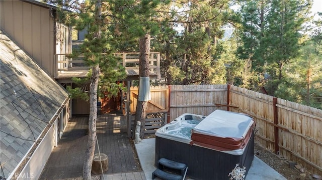 view of patio / terrace with a hot tub, fence, and a deck