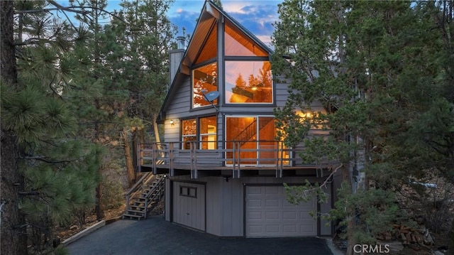 back of property with an attached garage, driveway, and stairway
