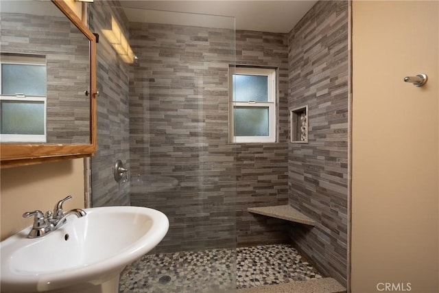 bathroom with walk in shower, a sink, and tile walls