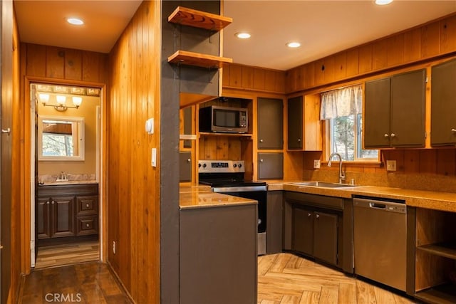 kitchen with open shelves, stainless steel appliances, a sink, and plenty of natural light