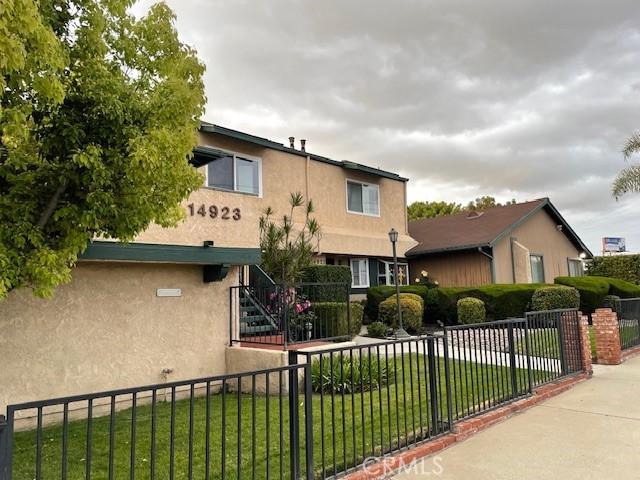 view of front of home featuring stucco siding, a front lawn, and fence private yard