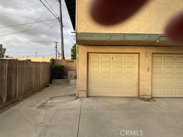 garage with concrete driveway and fence