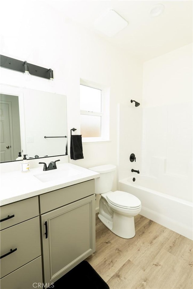 full bathroom featuring toilet, vanity, wood finished floors, and shower / bathing tub combination