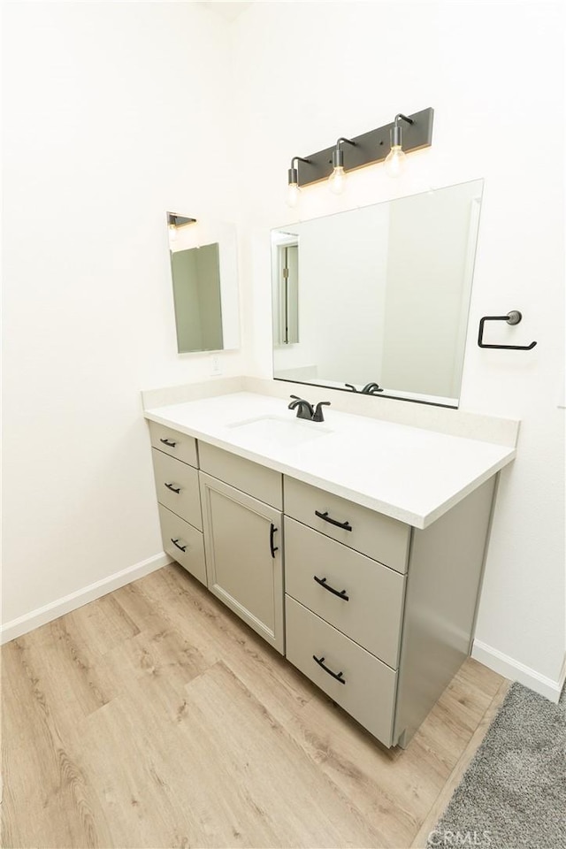 bathroom featuring baseboards, wood finished floors, and vanity