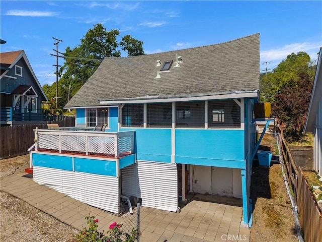 back of property featuring roof with shingles, fence, and a patio