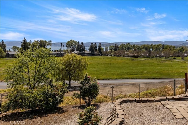 view of property's community with a yard, fence, and a mountain view