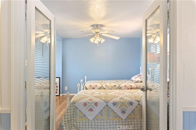 bedroom featuring baseboards, a ceiling fan, and wood finished floors