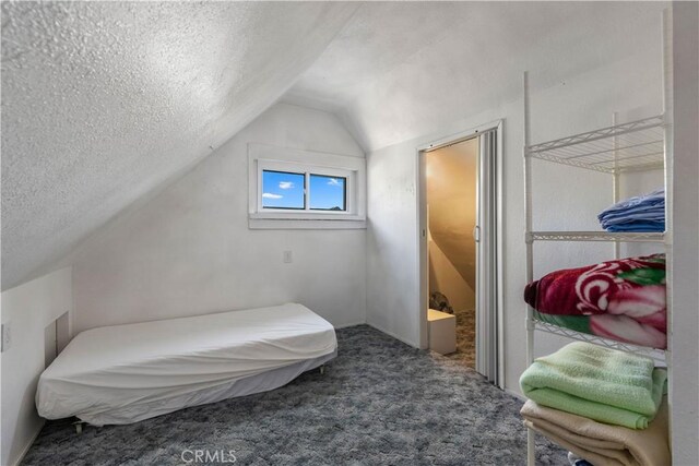 carpeted bedroom featuring lofted ceiling and a textured ceiling