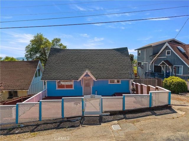 view of front facade featuring fence private yard and roof with shingles