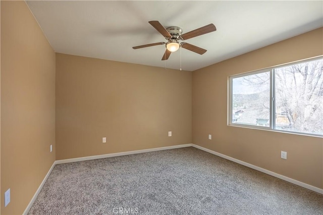carpeted spare room featuring ceiling fan and baseboards