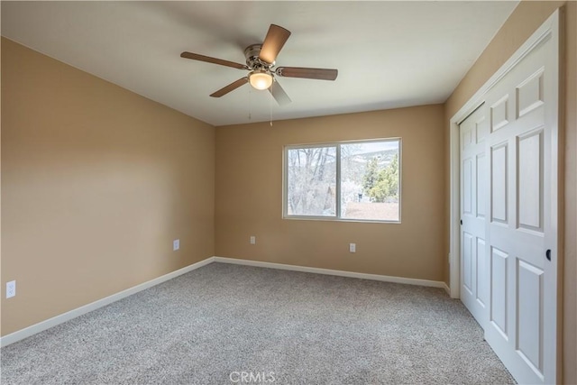 unfurnished bedroom featuring a closet, carpet flooring, baseboards, and ceiling fan