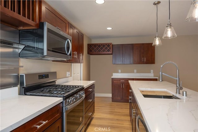 kitchen featuring a sink, light wood-style floors, pendant lighting, appliances with stainless steel finishes, and recessed lighting