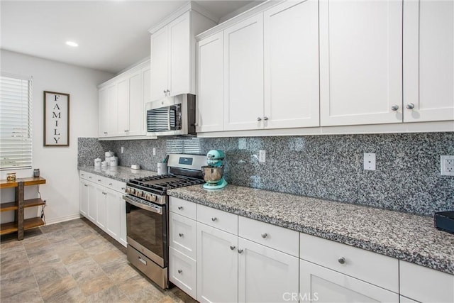 kitchen featuring white cabinets, stainless steel appliances, tasteful backsplash, baseboards, and light stone countertops