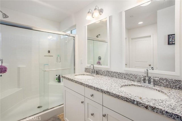 full bath with a sink, a shower stall, and double vanity