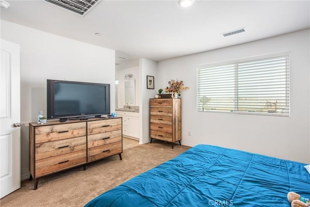 bedroom featuring ensuite bath, visible vents, and light colored carpet