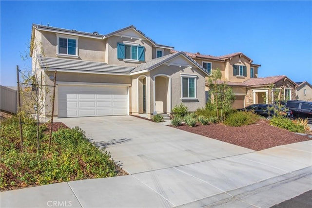 view of front of house with a tiled roof, an attached garage, concrete driveway, and stucco siding