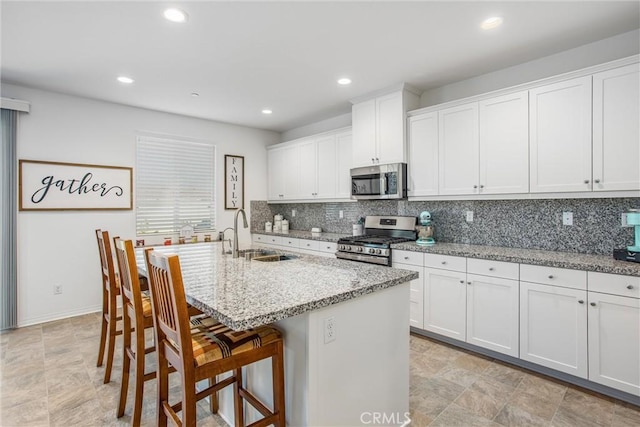 kitchen featuring backsplash, a center island with sink, stainless steel appliances, and a sink