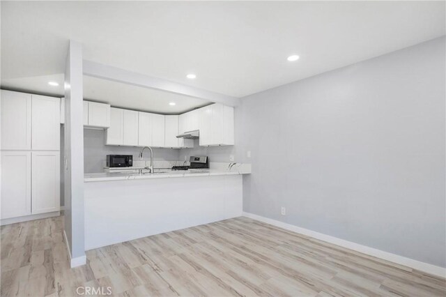 13261 Coast St, Garden Grove, CA 92844 - kitchen featuring black microwave, stove, baseboards, light countertops, and white cabinetry