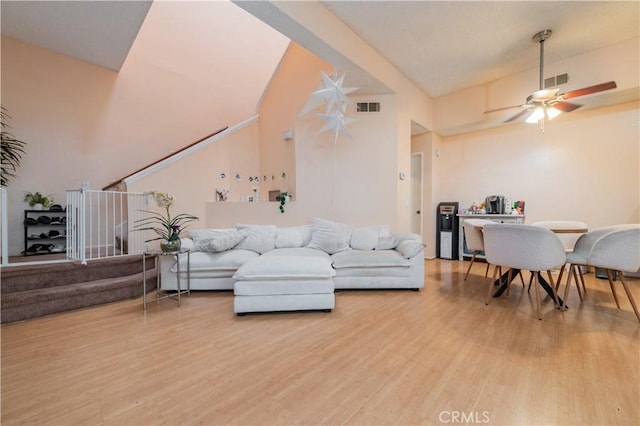living room with wood finished floors, visible vents, stairway, and a ceiling fan
