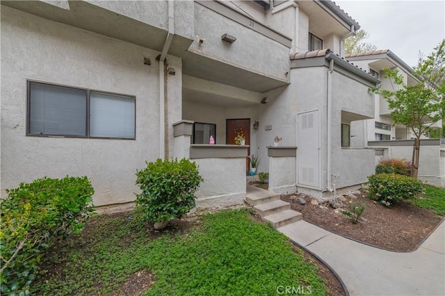 doorway to property featuring a tile roof and stucco siding