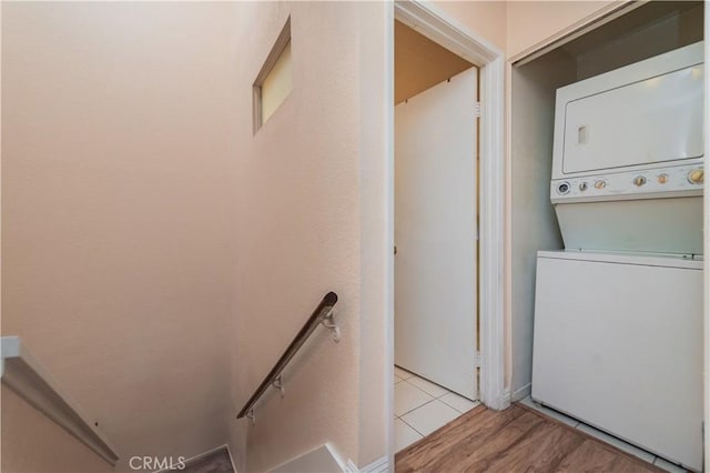 washroom with stacked washing maching and dryer, light wood-type flooring, and laundry area