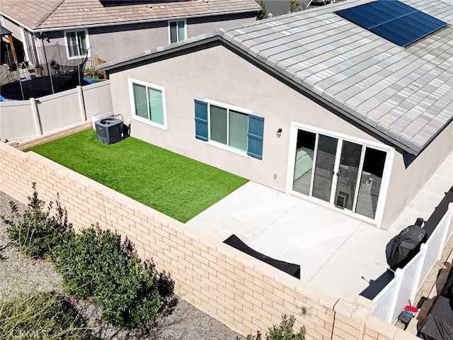 rear view of property featuring a fenced backyard, central AC, a yard, a patio, and stucco siding