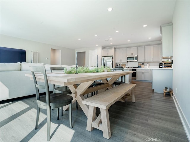 dining room with baseboards, wood finished floors, and recessed lighting