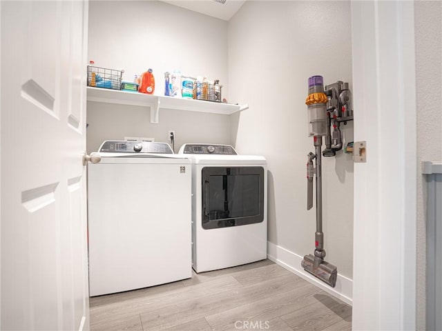 washroom featuring light wood-style floors, washing machine and clothes dryer, baseboards, and laundry area