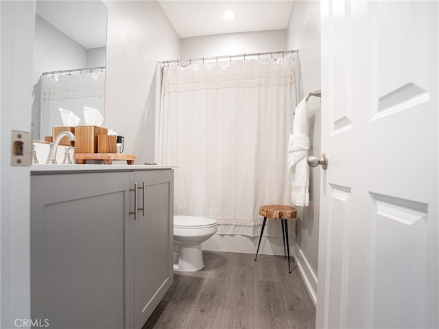 full bathroom featuring toilet, vanity, wood finished floors, and shower / bath combo with shower curtain