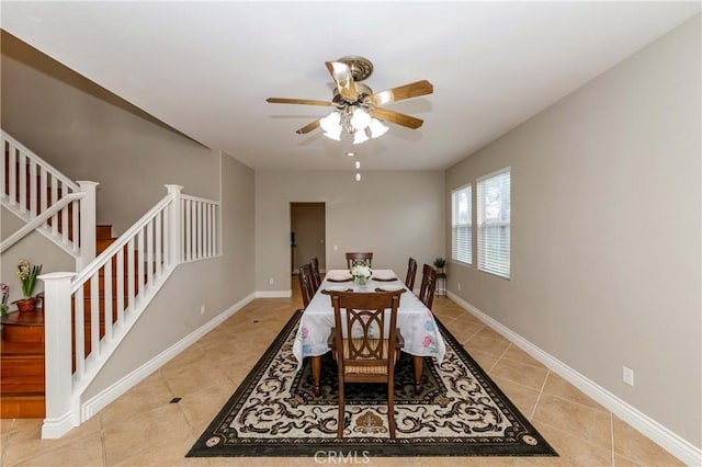 dining room featuring baseboards, stairs, ceiling fan, and light tile patterned flooring