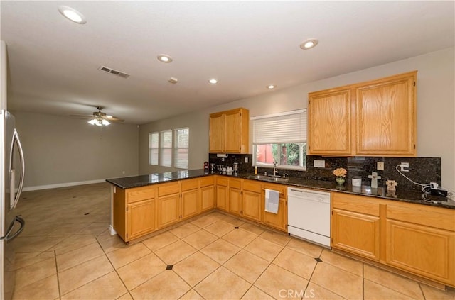 kitchen with a peninsula, a sink, visible vents, decorative backsplash, and dishwasher
