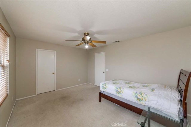 bedroom featuring ceiling fan, visible vents, baseboards, and light carpet