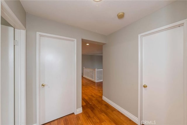 corridor with recessed lighting, light wood-style floors, baseboards, and an upstairs landing
