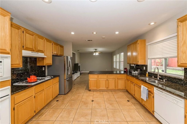kitchen with a sink, decorative backsplash, white appliances, a peninsula, and under cabinet range hood