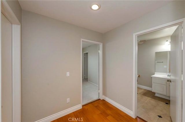 unfurnished bedroom with light wood-style floors, baseboards, and a sink