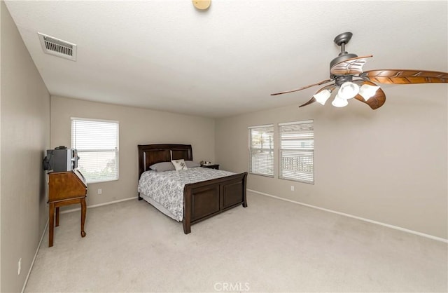 bedroom featuring visible vents, baseboards, multiple windows, and light colored carpet