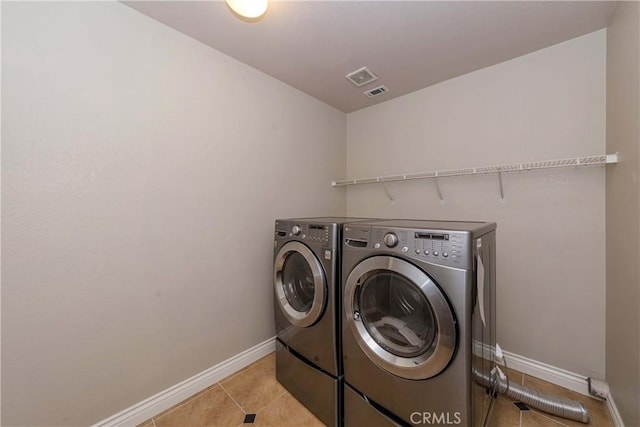 laundry area with washing machine and dryer, baseboards, laundry area, and light tile patterned floors