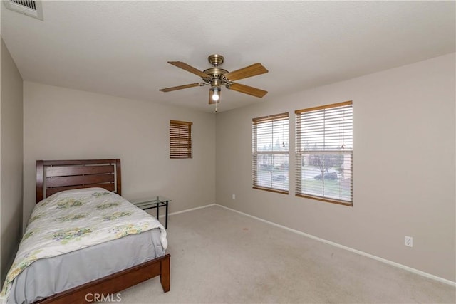 bedroom with visible vents, a ceiling fan, baseboards, and light colored carpet