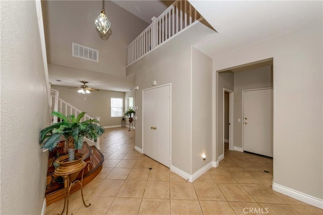 entryway with a towering ceiling, baseboards, visible vents, stairway, and light tile patterned floors