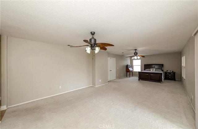 unfurnished living room with light carpet, a ceiling fan, and baseboards
