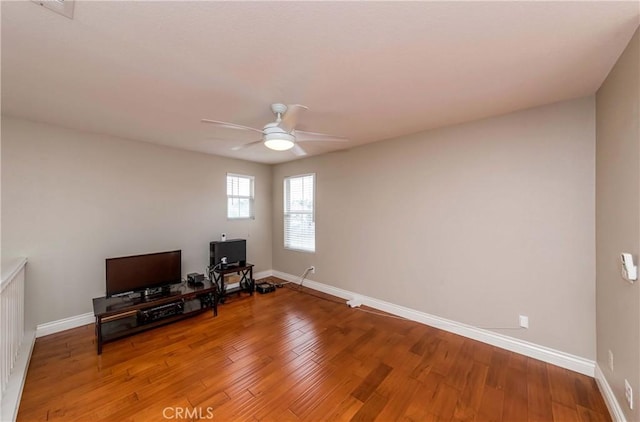 living area featuring ceiling fan, baseboards, and wood finished floors