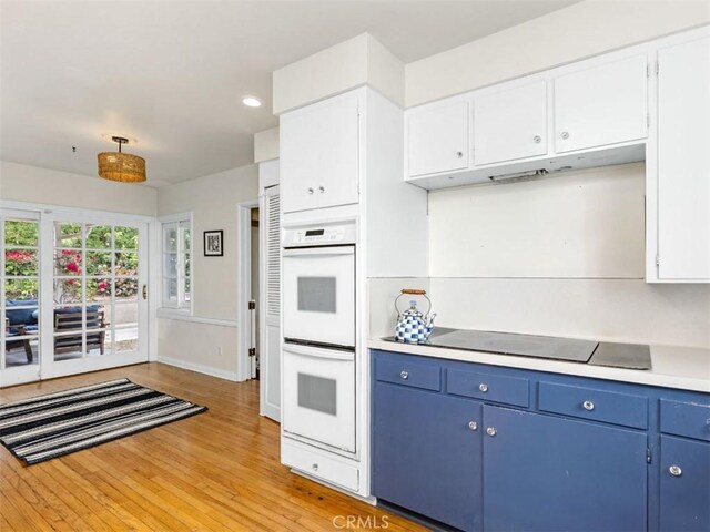 322 Calle De Arboles, Redondo Beach, CA 90277 - kitchen with double oven, blue cabinets, black electric stovetop, light countertops, and light wood-style floors
