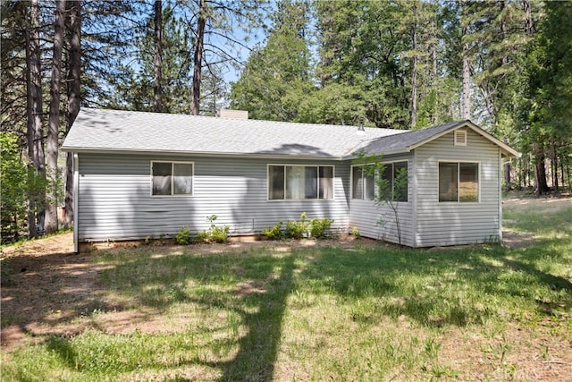 rear view of house with a lawn and a shingled roof
