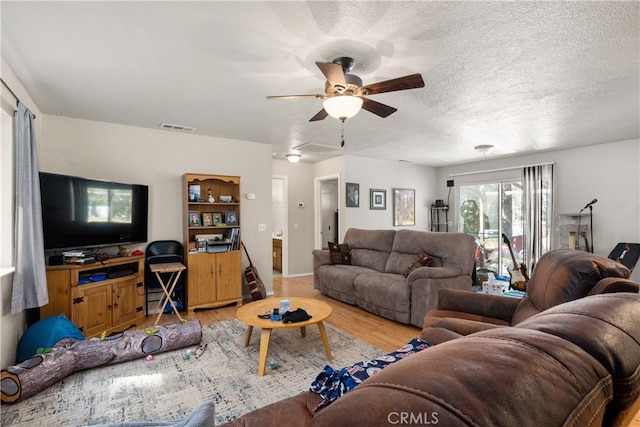 living area featuring light wood finished floors, visible vents, and ceiling fan